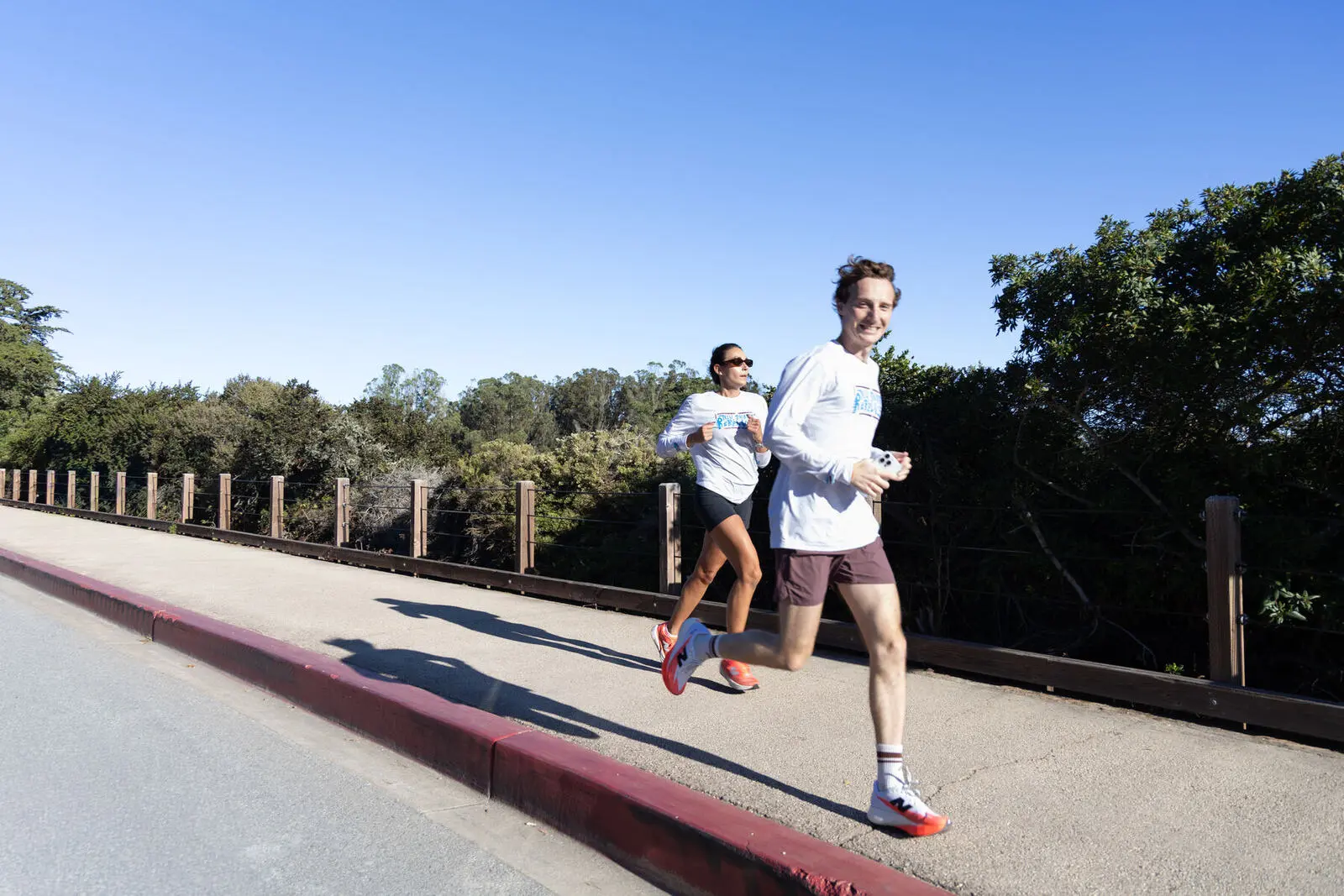 Two runners on a sunny overpass